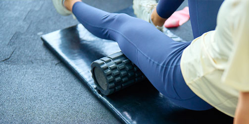 Woman foam rolling knee Woman foam rolling knee
