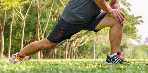 Man stretching knee in park Man stretching knee in park